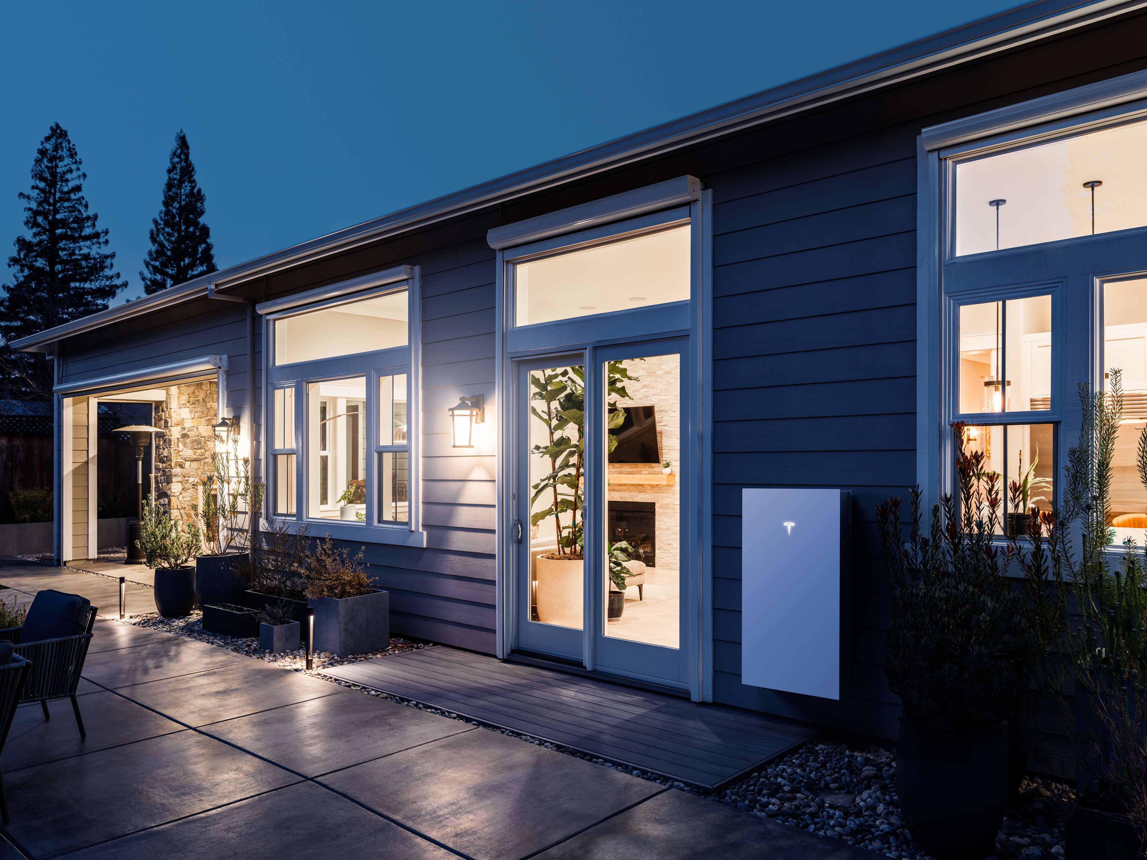 A Tesla Powerwall 3 battery on the side of a house at night