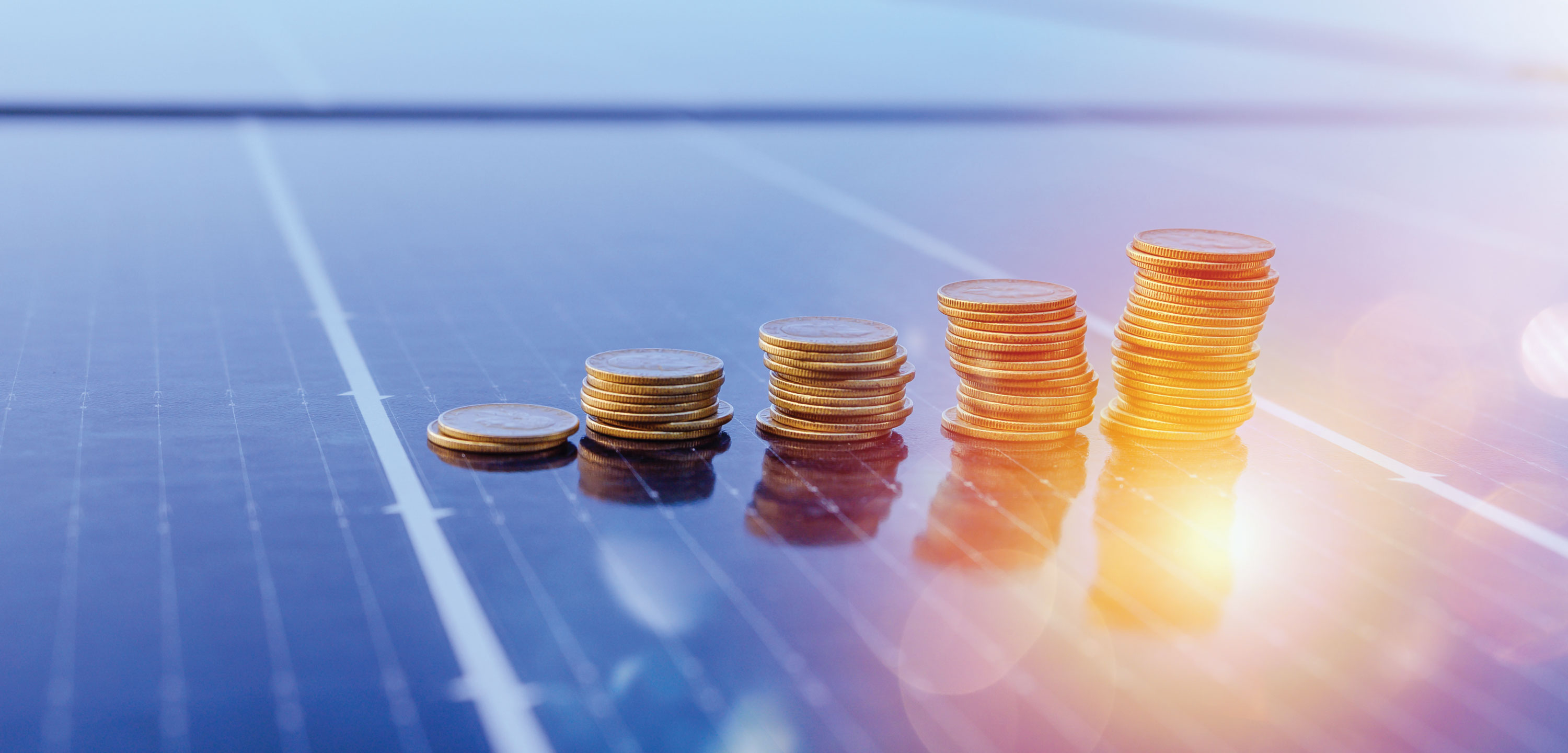 Stacks of quarters on a solar panel with a sunbeam reflecting off of it