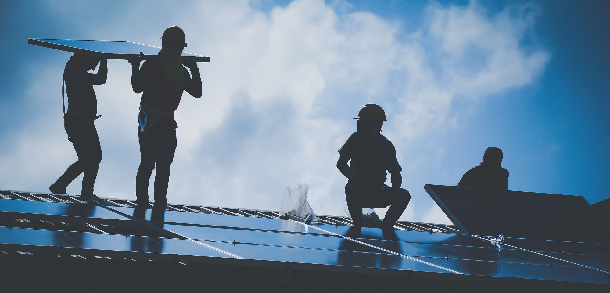 silhouette of solar installers working on a roof